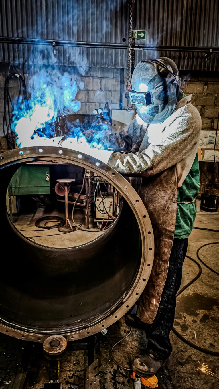 A welder engaged in a welding process inside a factory in Brazil. Sparks and smoke illustrate a dynamic industrial scene.